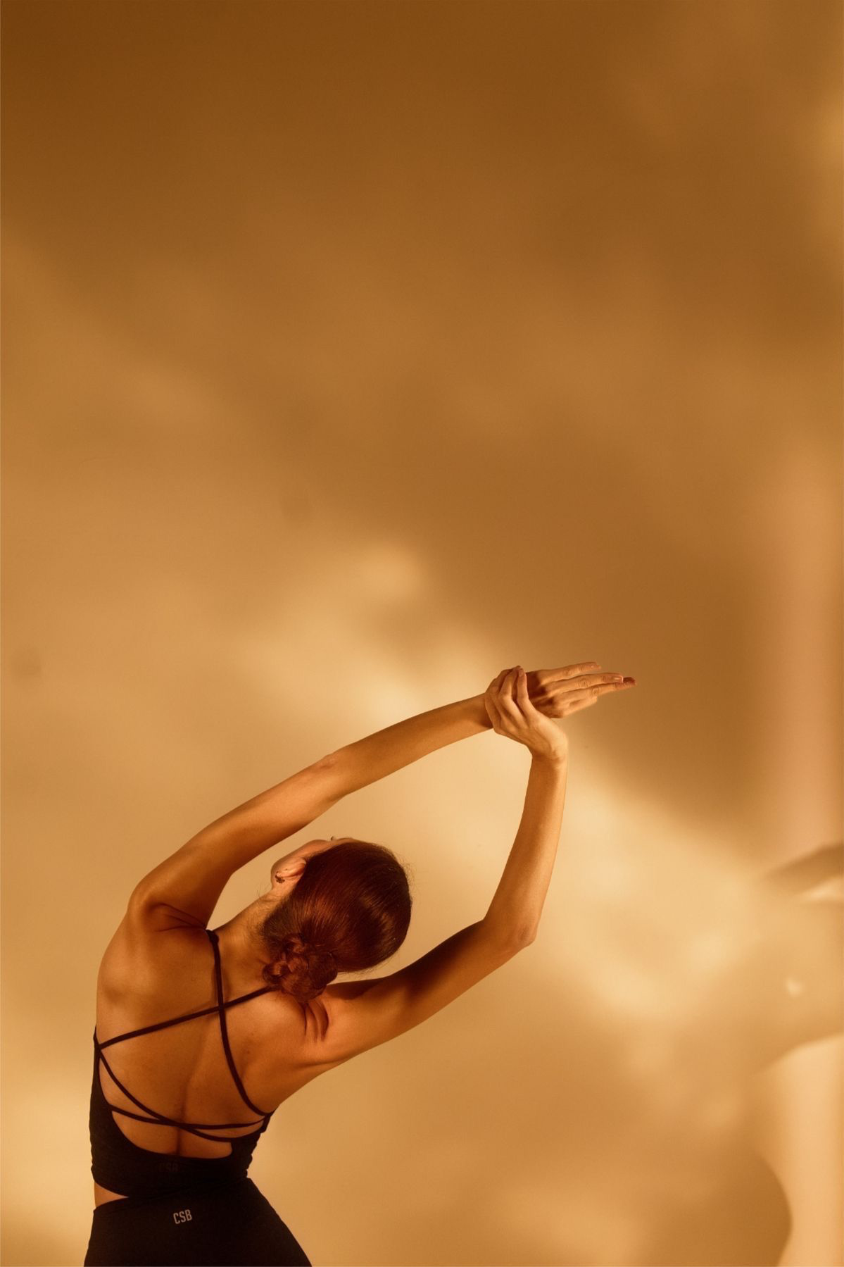 A woman stretching overhead in warm golden sunlight